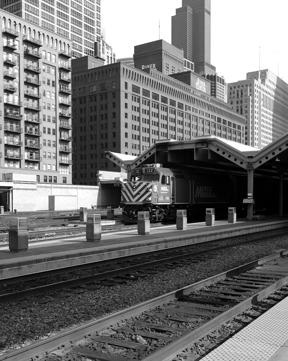black and white photos of a single Metra engine contrasted against Chicago buildings.