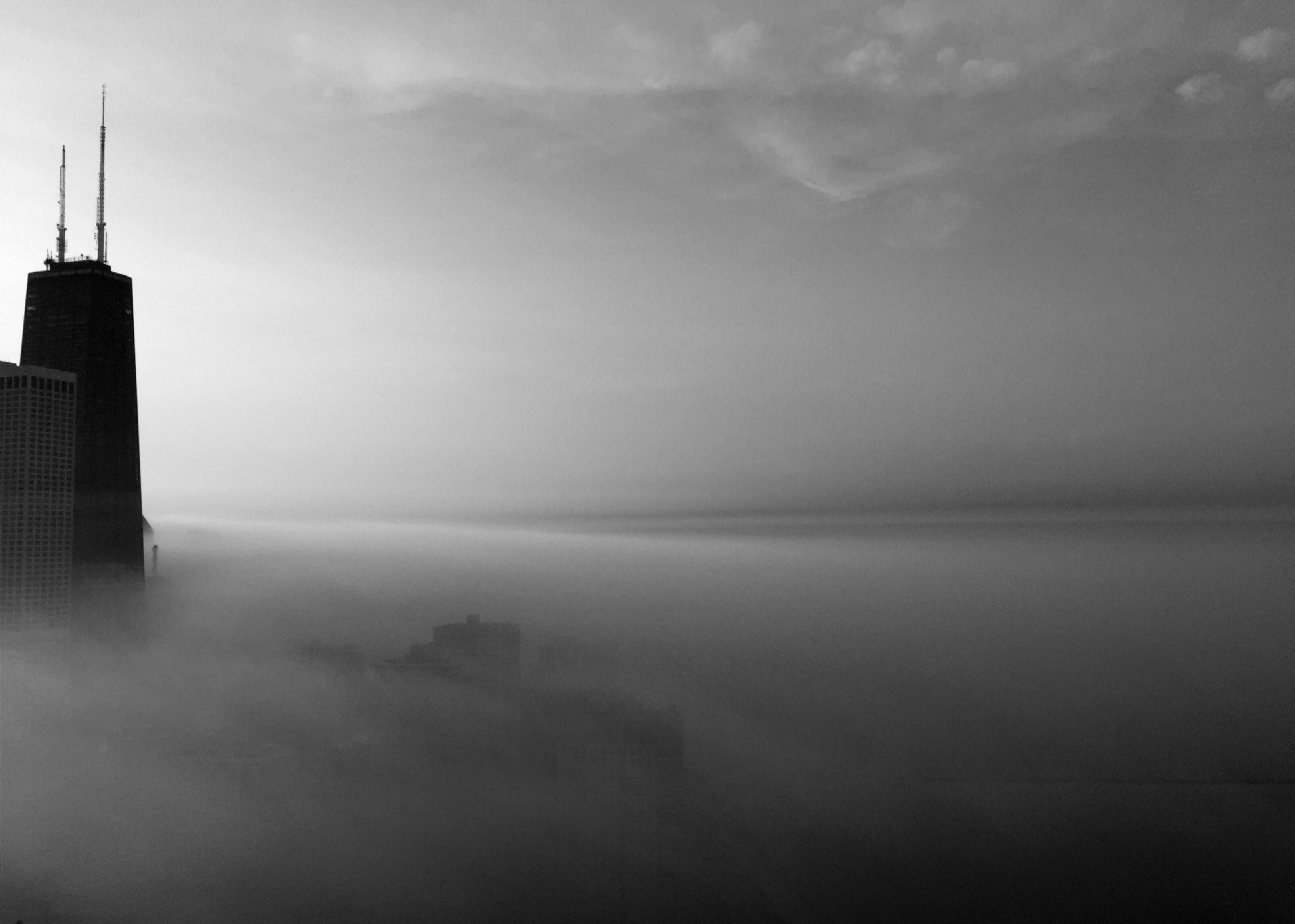 black and white photos of the chicago skyline piercing through thick fog