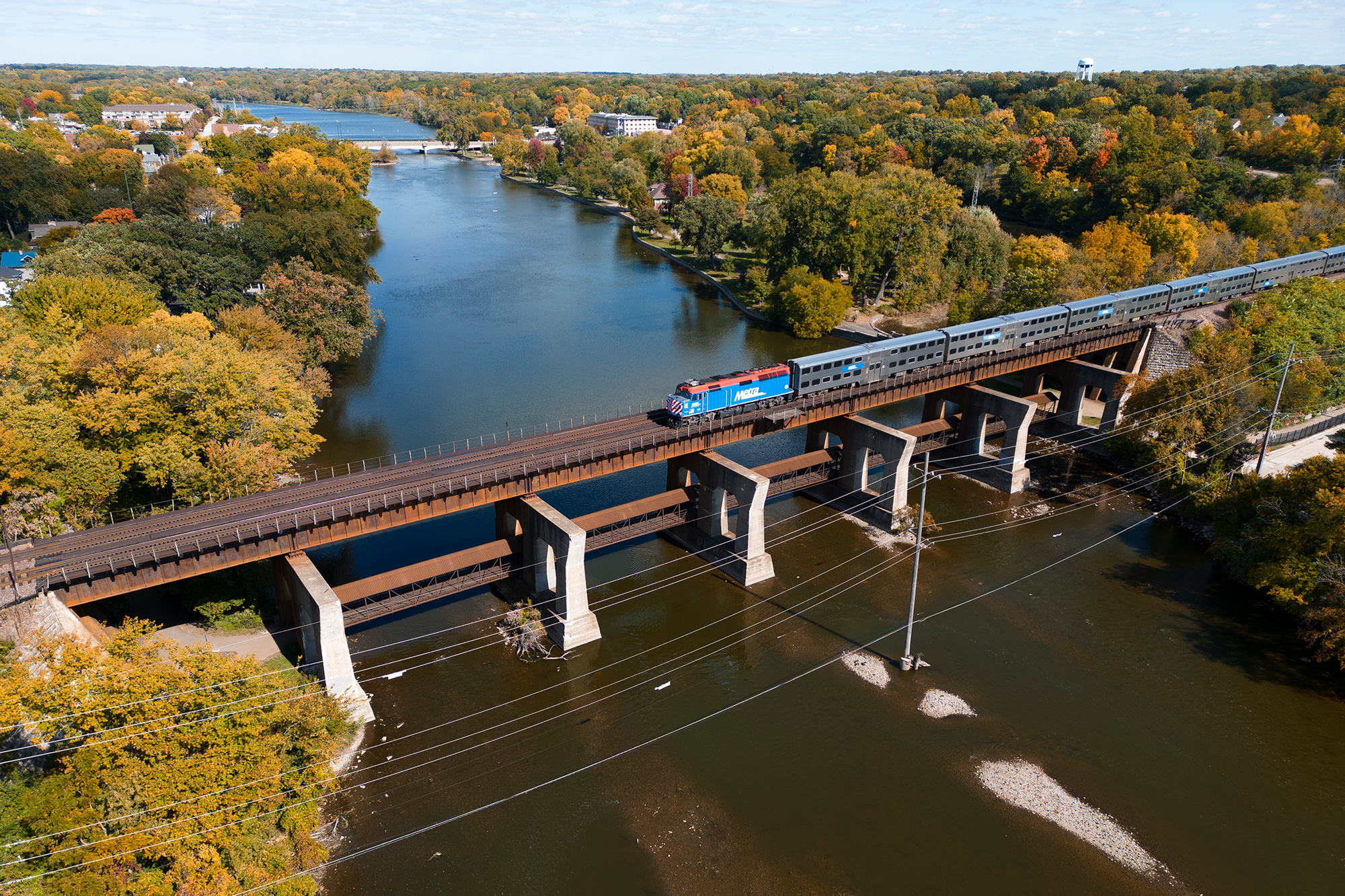 a outbound Metra train crosses over the Fox river in Geneva, IL. as captured from a drone.