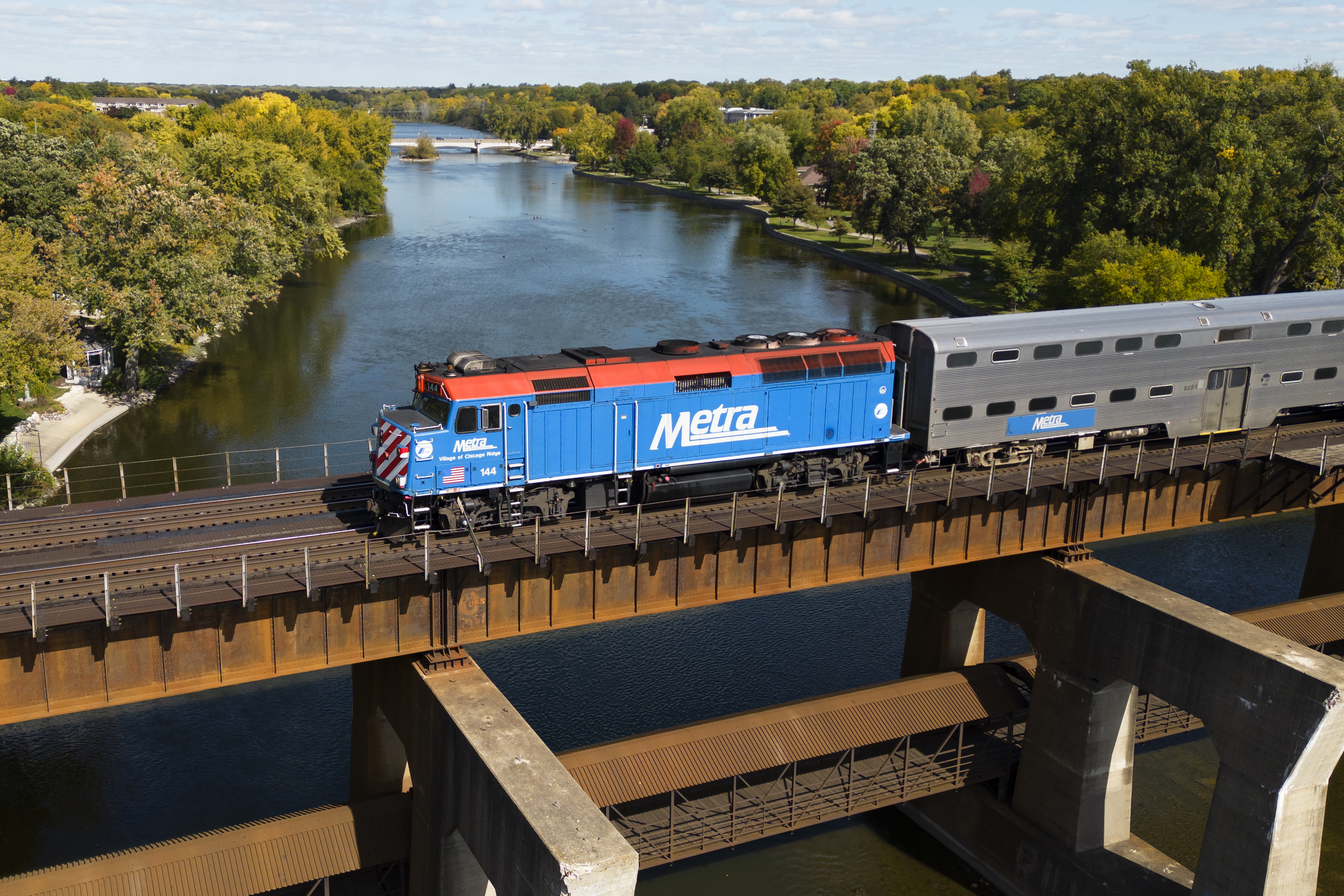 a outbound Metra train crosses over the Fox river in Geneva, IL. as captured from a drone.