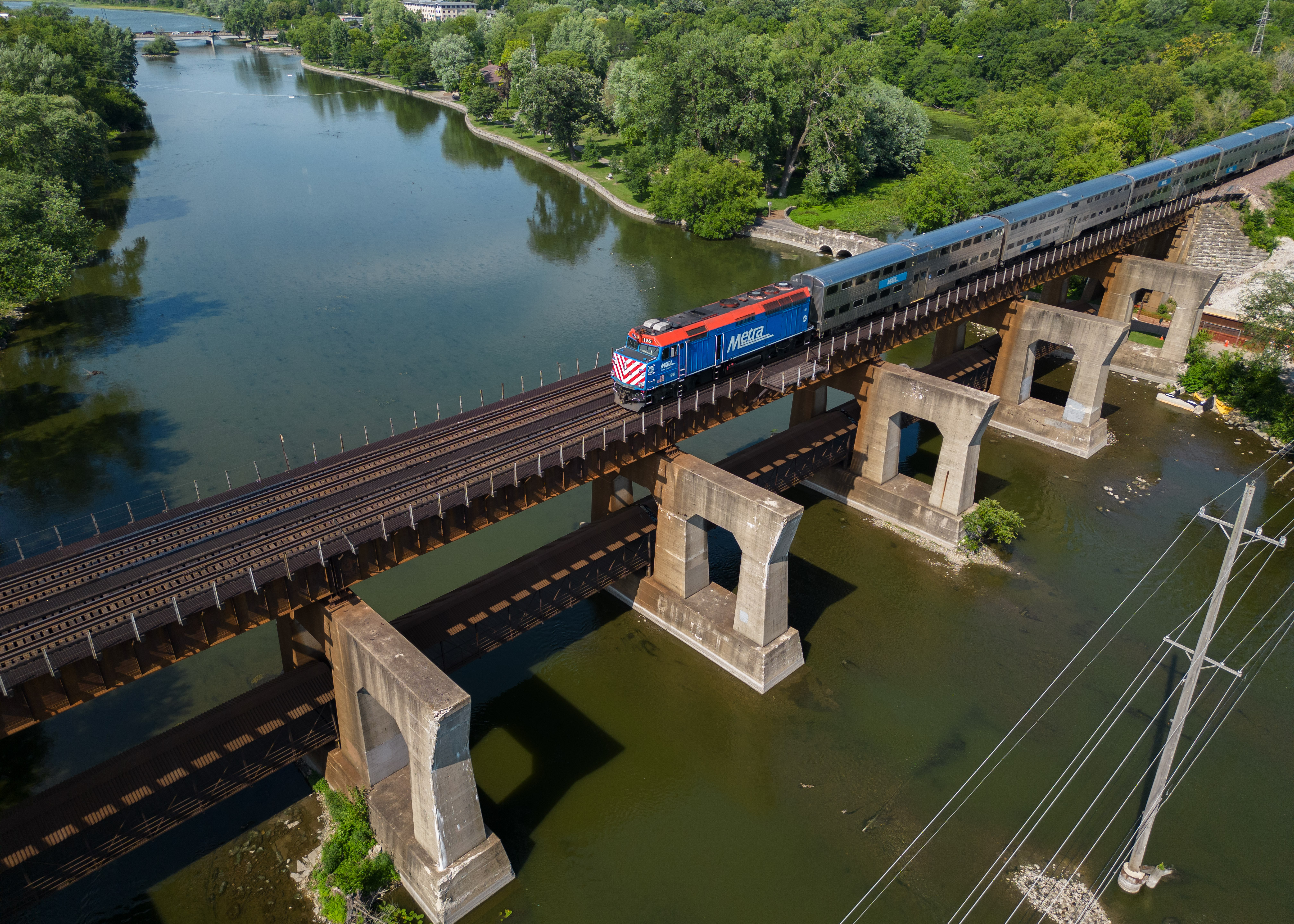 a outbound Metra train crosses over the Fox river in Geneva, IL. as captured from a drone.