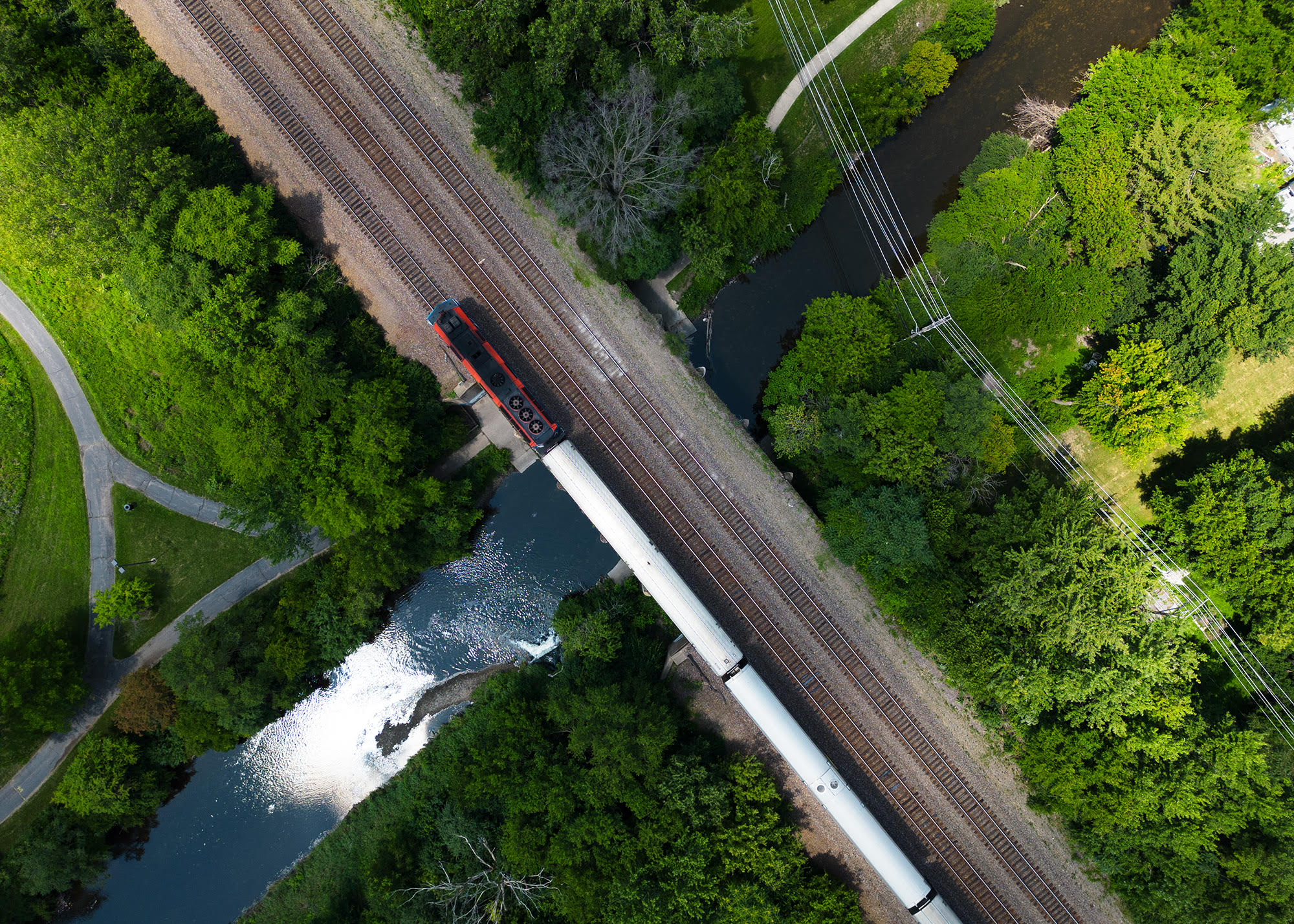 a outbound Metra train crosses over the Fox river in Geneva, IL. as captured from a drone.