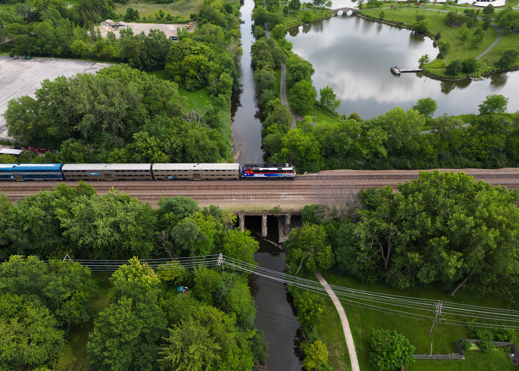 a outbound Metra train crosses over the Fox river in Geneva, IL. as captured from a drone.